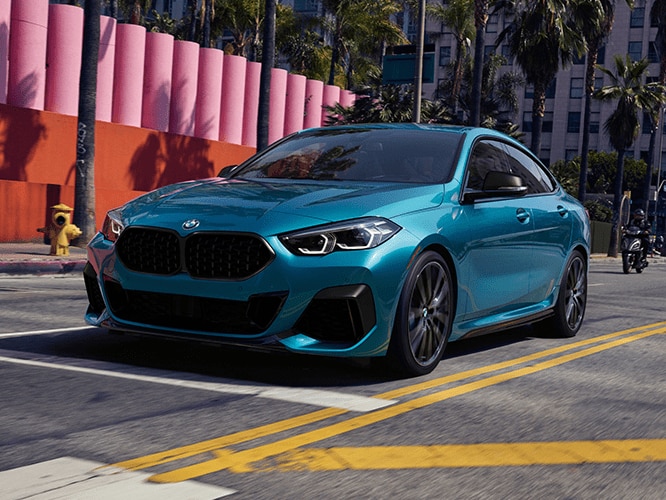 The BMW 2 Series Gran Coupe in Snapper Rocks Blue Metallic driving through street with colorful structures