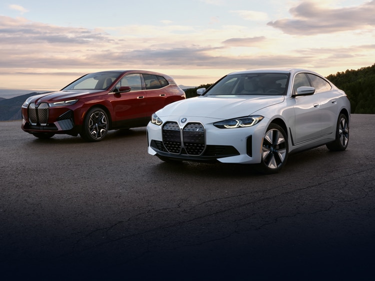 An electric BMW iX & i4 parked side-by-side outside