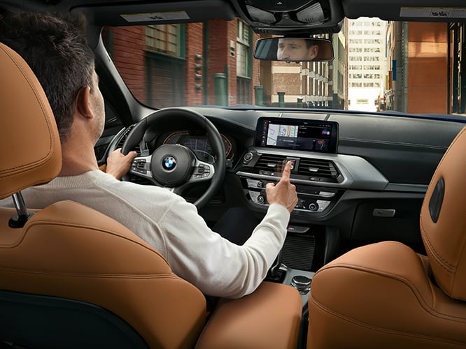 Interior shot of BMW with driver utilizing the advance technology while cruising through the city