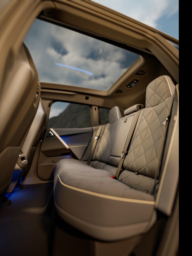 Interior shot of rear seats inside a 2025 BMW iX to emphasize the spacious leg room and panoramic moon roof.