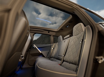 Interior shot of rear seats inside a 2025 BMW iX to emphasize the spacious leg room and panoramic moon roof.