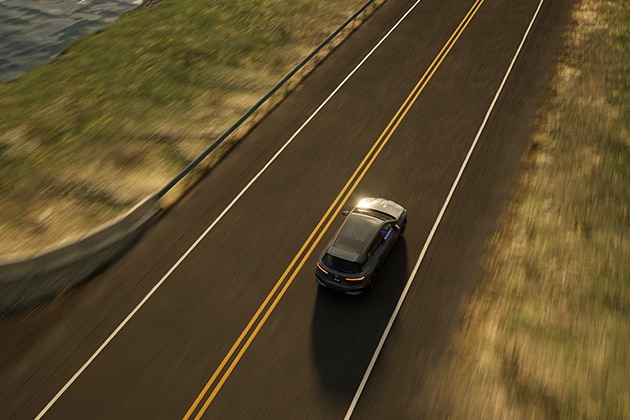 Birds-eye view of a 2025 BMW iX zipping down an seaside highway.
