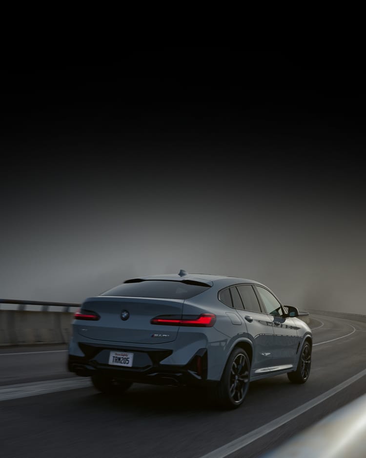 Rear shot of 2025 BMW X4 M40i driving down a foggy and curvy road