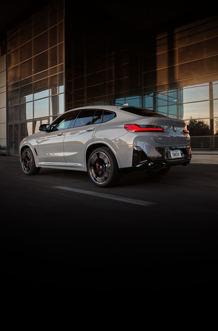 Rear profile shot of the 2025 BMW X4 M40i driving down a city street
