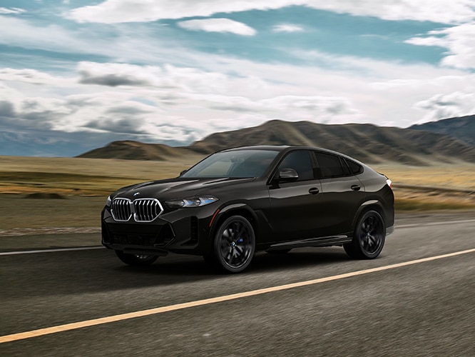 Exterior shot of the 2026 BMW X6 xDrive40i in motion on a rural highway