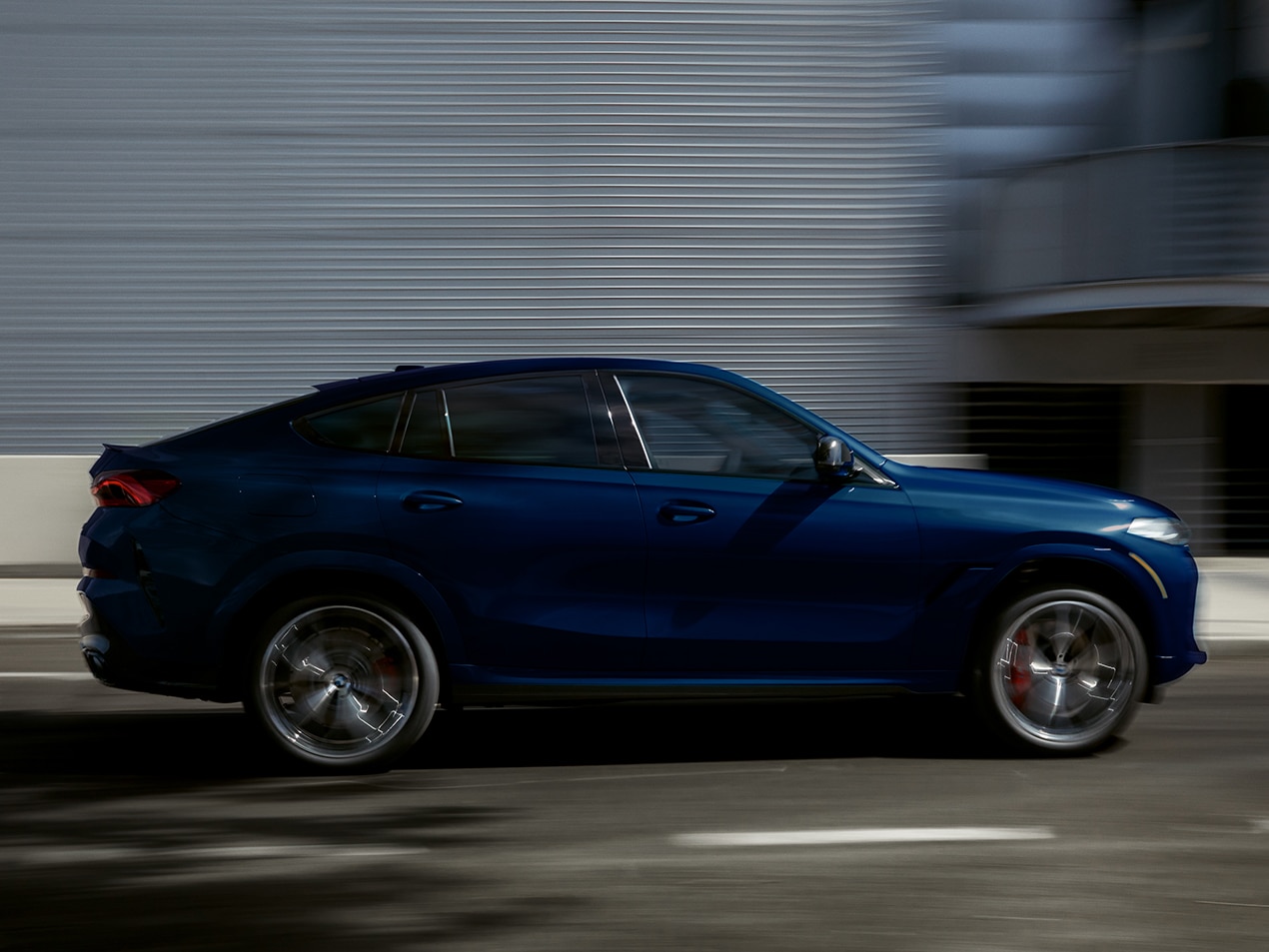 Profile of the 2026 BMW X6 in motion on a city street 